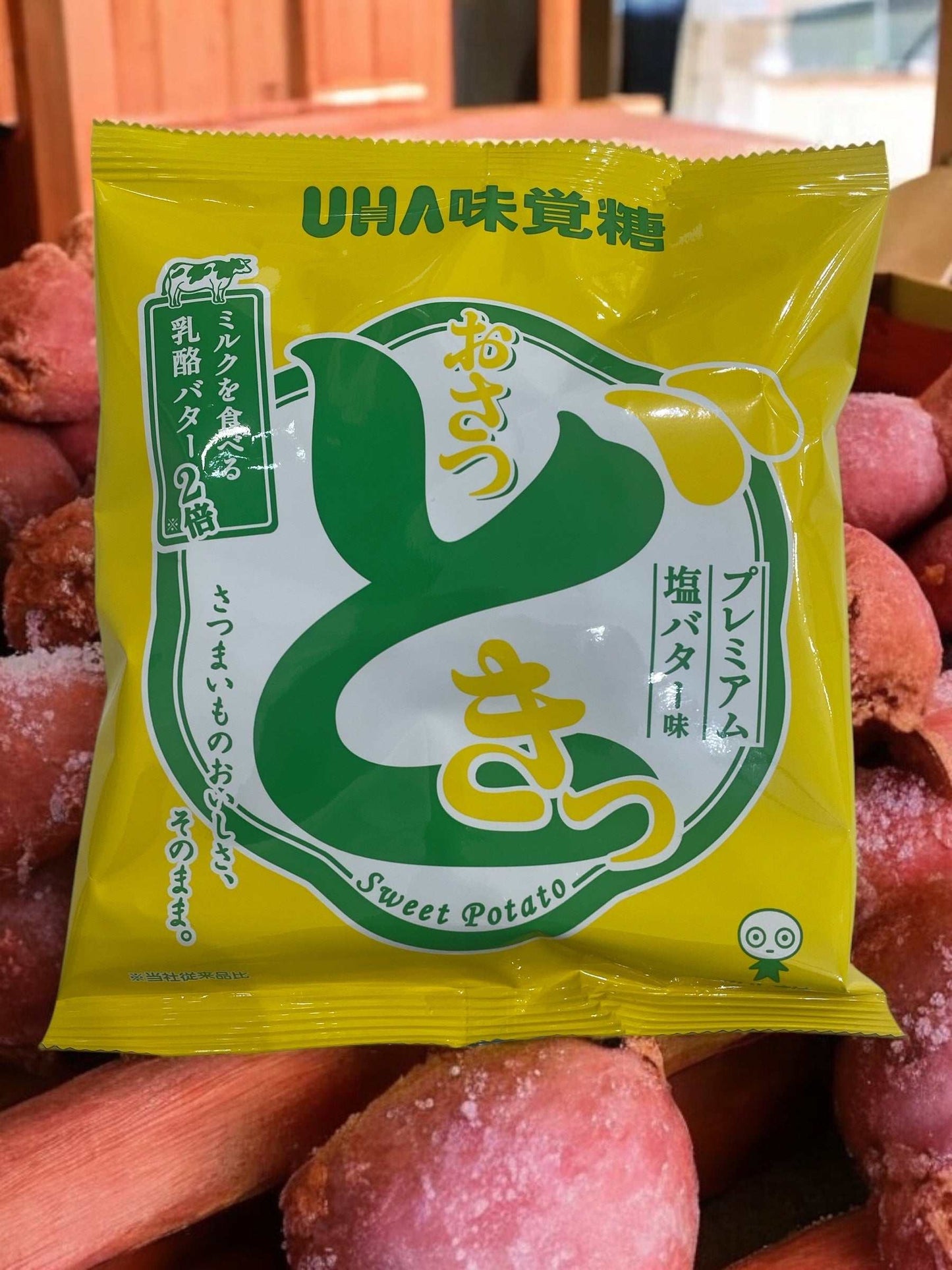 UHA味覚糖 おさつどきっ premium salted butter sweet potato chips 65g package on sweet potatoes background